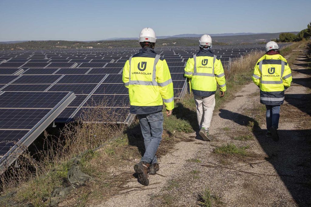 Trois collaborateurs Urbasolar longeant une centrale solaire au sol
