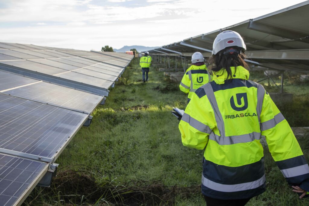Équipe Urbasolar en tenue de sécurité inspectant une centrale solaire au sol